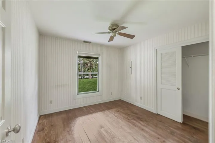 Unfurnished bedroom with ceiling fan, a closet, and wood-type flooring