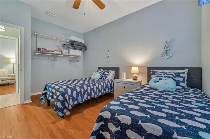 Bedroom featuring ceiling fan, visible vents, baseboards, and wood finished floors