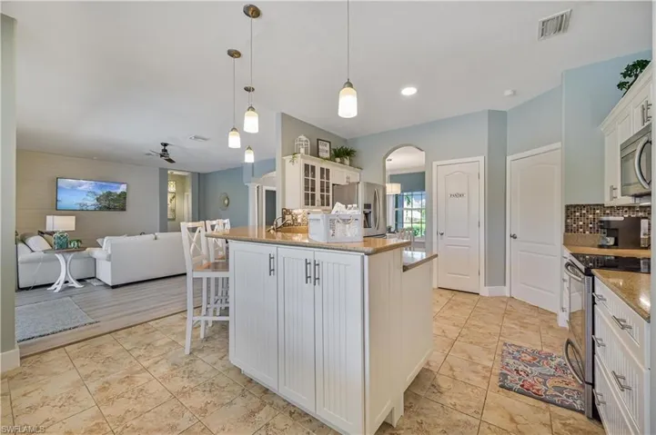 Kitchen with visible vents, backsplash, glass insert cabinets, appliances with stainless steel finishes, and arched walkways