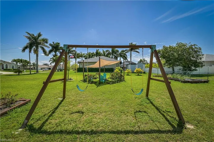 View of playground featuring a lawn and fence