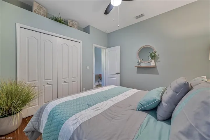 Bedroom featuring a ceiling fan, wood finished floors, visible vents, and a closet