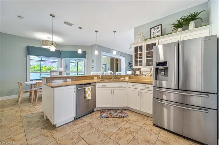 Kitchen featuring visible vents, a peninsula, a sink, stainless steel appliances, and white cabinetry