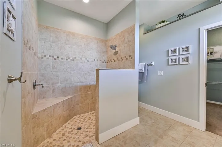 Full bathroom with tile patterned flooring, a spacious closet, baseboards, and walk in shower