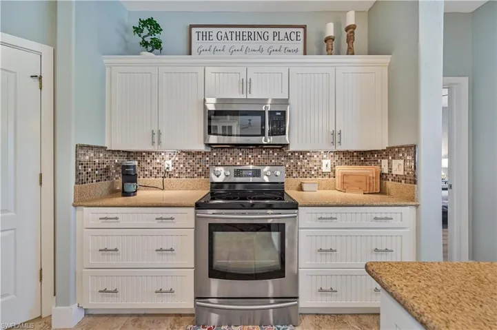 Kitchen featuring decorative backsplash, white cabinets, and stainless steel appliances