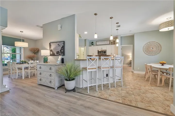 Kitchen featuring visible vents, a peninsula, light wood-style flooring, white cabinetry, and stainless steel microwave