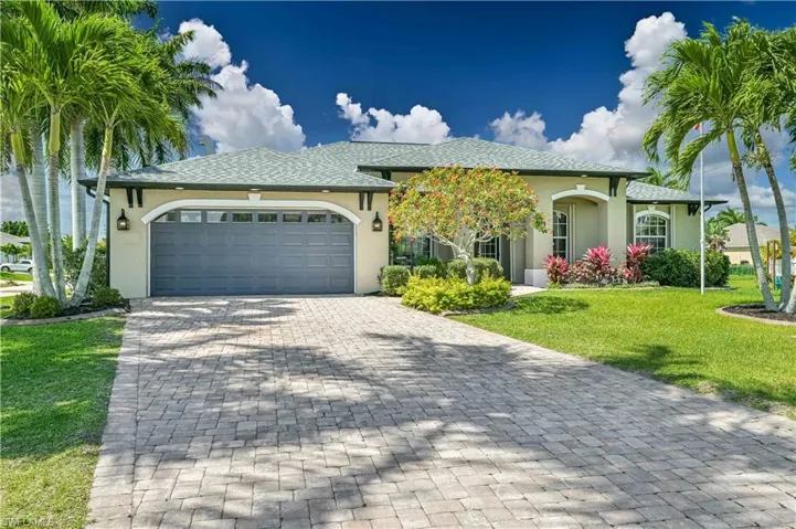 View of front of home with a front yard, decorative driveway, a garage, and stucco siding