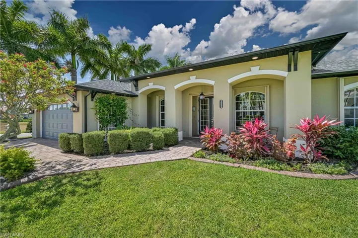 View of front of property with a front yard, roof with shingles, driveway, an attached garage, and stucco siding