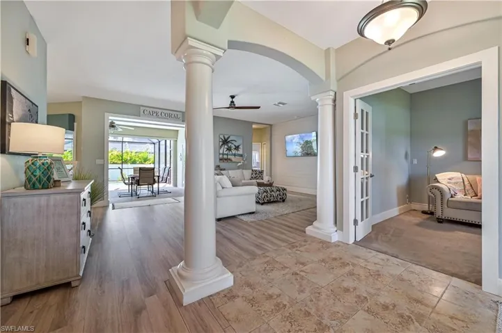 Foyer featuring wood finished floors, decorative columns, a ceiling fan, and arched walkways