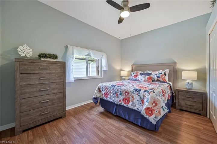 Bedroom featuring a ceiling fan, lofted ceiling, wood finished floors, and baseboards