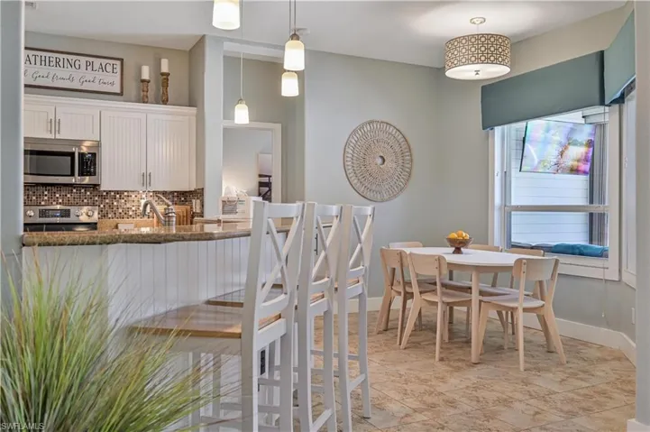 Kitchen featuring dark stone counters, decorative backsplash, white cabinets, appliances with stainless steel finishes, and pendant lighting