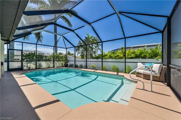 View of swimming pool with glass enclosure, a patio area, and a fenced in pool