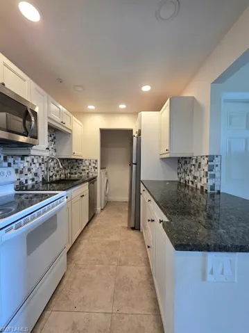 Kitchen featuring appliances with stainless steel finishes, dark countertops, light wood-style flooring, a textured ceiling, and washer / clothes dryer
