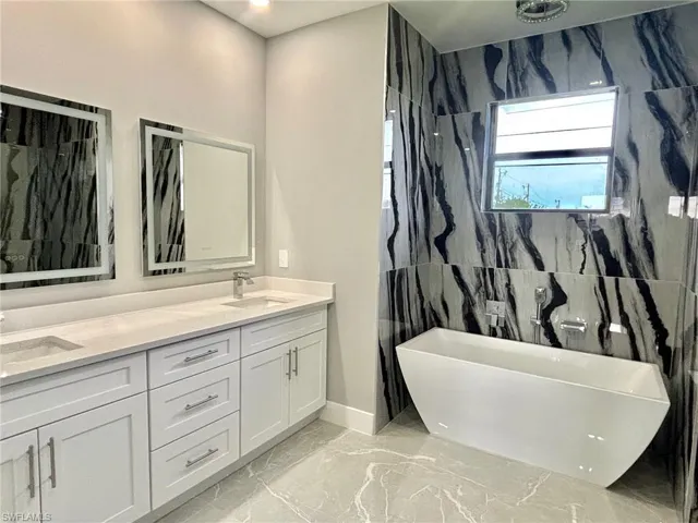 Bathroom with a bathing tub, vanity, and tile patterned floors