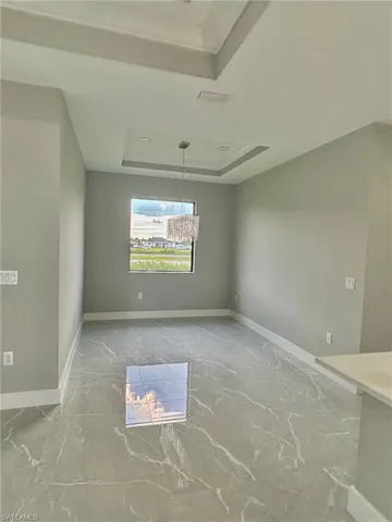 Empty room featuring a tray ceiling and tile patterned flooring