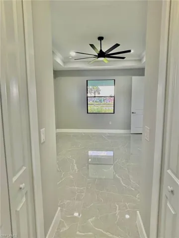 Tiled spare room with a tray ceiling, ceiling fan, and ornamental molding