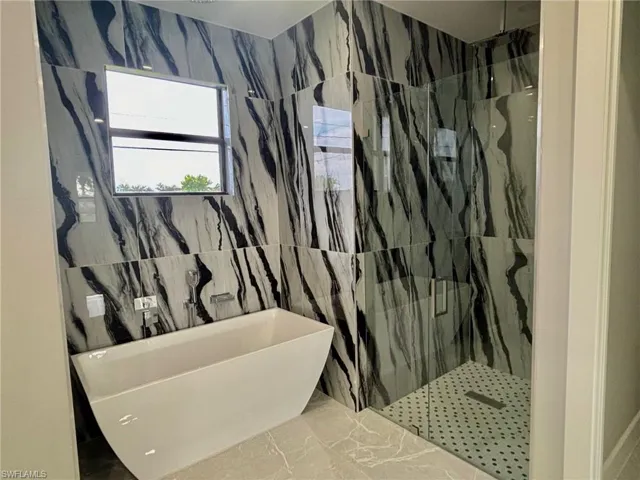 Bathroom with tile walls, separate shower and tub, and tile patterned floors