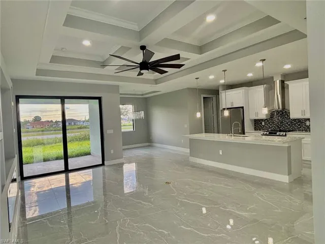 Kitchen with beam ceiling, wall chimney exhaust hood, coffered ceiling, tile patterned floors, and ceiling fan