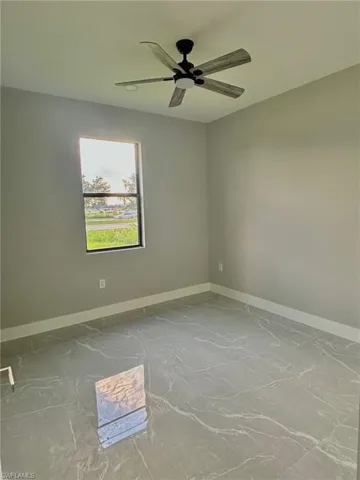 Tiled empty room featuring ceiling fan