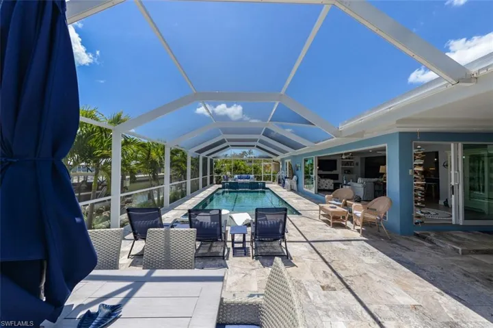 View of pool with glass enclosure, ceiling fan, and a patio