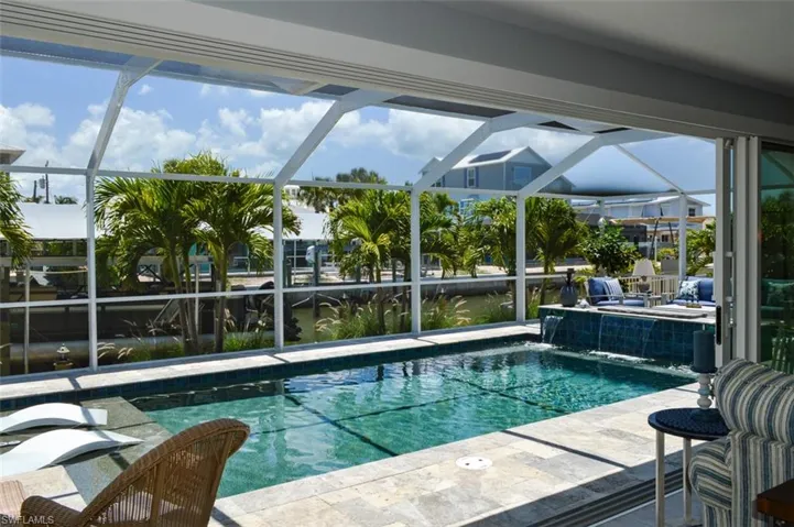 View of pool with a patio, pool water feature, and glass enclosure