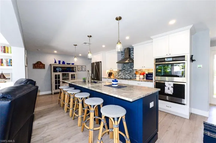 Kitchen featuring a center island with sink, decorative light fixtures, and appliances with stainless steel finishes