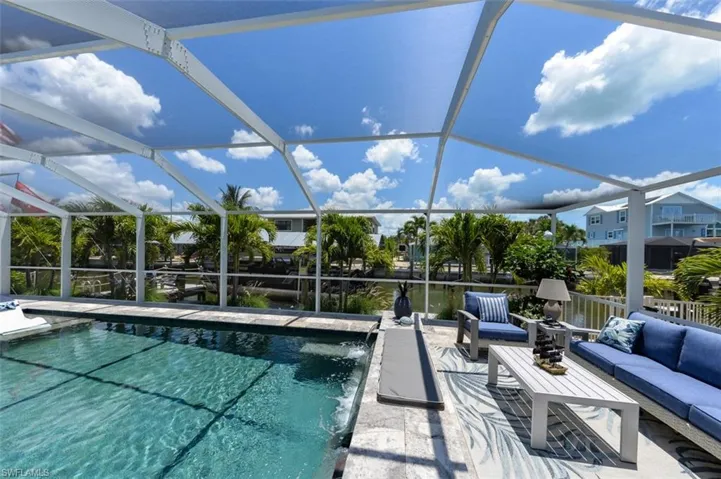 View of swimming pool with glass enclosure, pool water feature, a patio area, and an outdoor hangout area