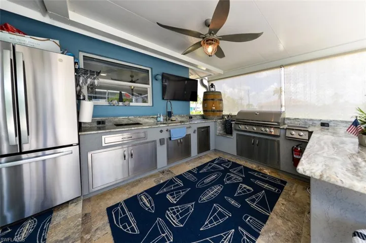 Kitchen with gray cabinets, stainless steel fridge, sink, and ceiling fan