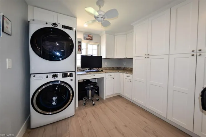 Washroom with stacked washer / drying machine, light hardwood / wood-style floors, and ceiling fan