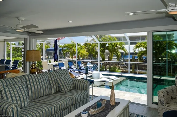 View from the living room of swimming pool featuring a lanai, a patio area, an outdoor living space