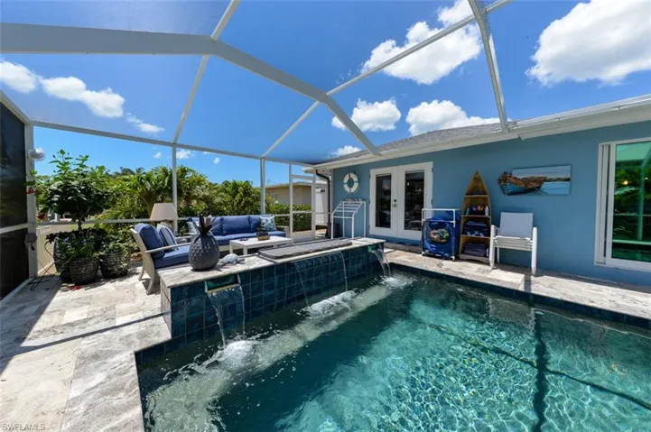 View of swimming pool with pool water feature, glass enclosure, a patio area, and french doors