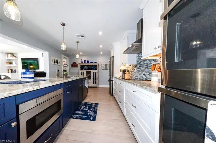 Kitchen with white cabinetry, sink, hanging light fixtures, and stainless steel appliances