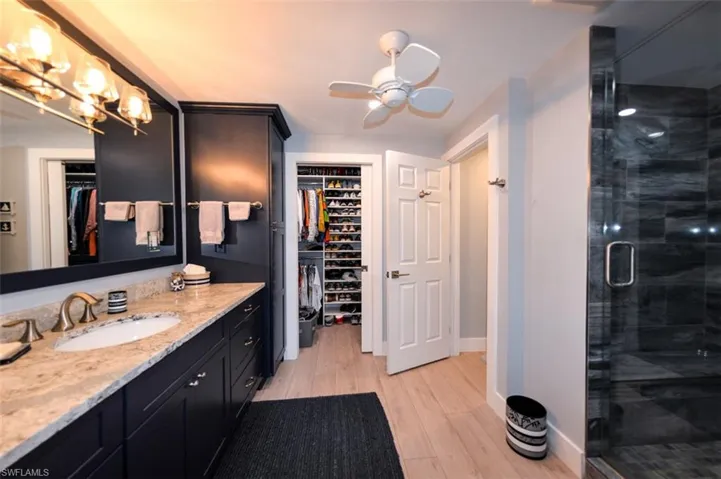 Bathroom  vanity, ceiling fan, and an enclosed shower