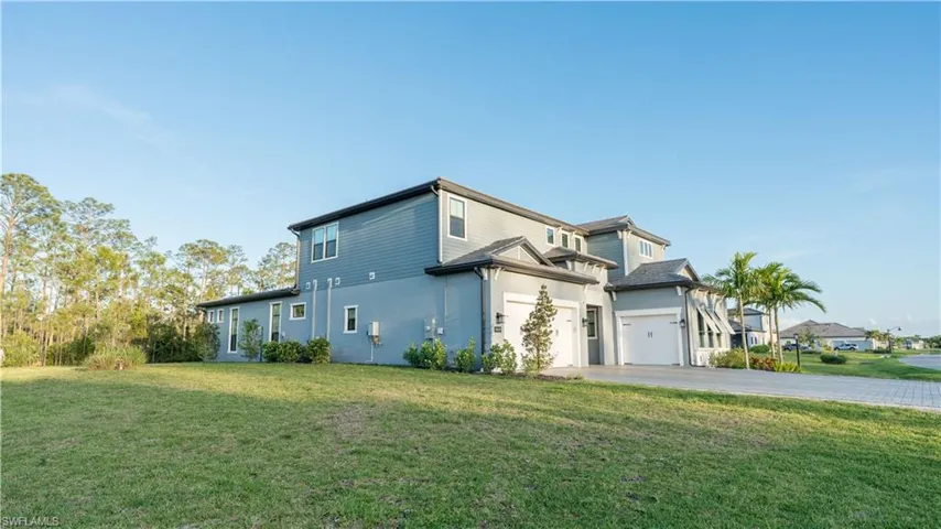 View of side of property featuring a lawn, a garage, stucco siding, and driveway