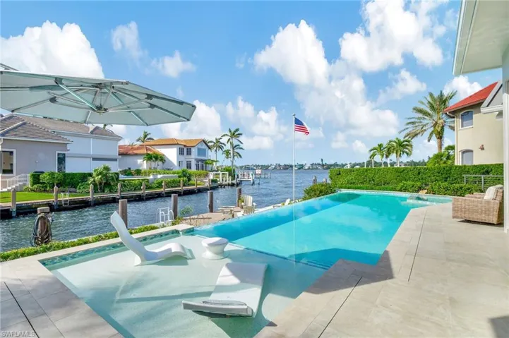 View of infinity edge pool with a patio area and a water view