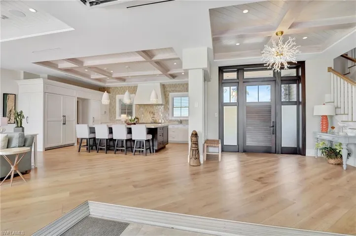 Foyer featuring beamed ceiling, light hardwood flooring, a chandelier, and coffered ceiling
