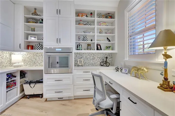 Butler's pantry with built in desk and light wood flooring
