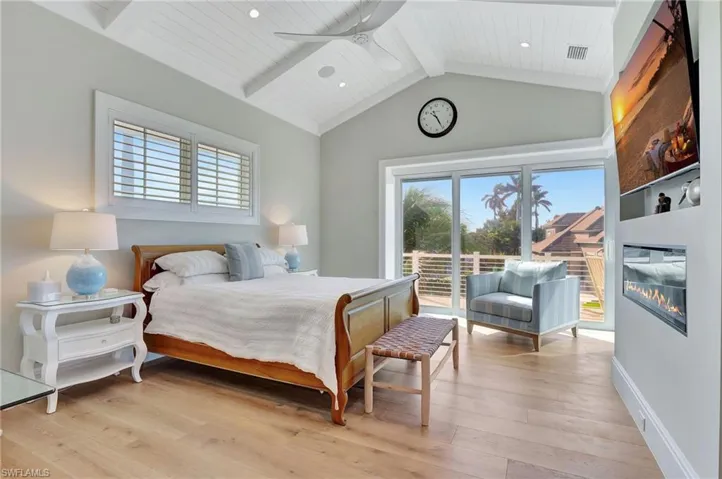 Upstairs Primary Bedroom with wood vaulted ceiling, ceiling fan, fireplace, light hardwood flooring, beamed ceiling, with private access to upstairs balcony