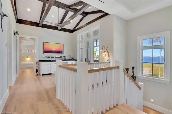 Hallway featuring wood ceiling, beam ceiling, light hardwood flooring, a water view, and high vaulted ceiling