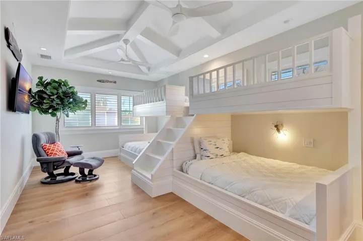 Bedroom with light hardwood flooring, beam ceiling, coffered ceiling, and ceiling fan