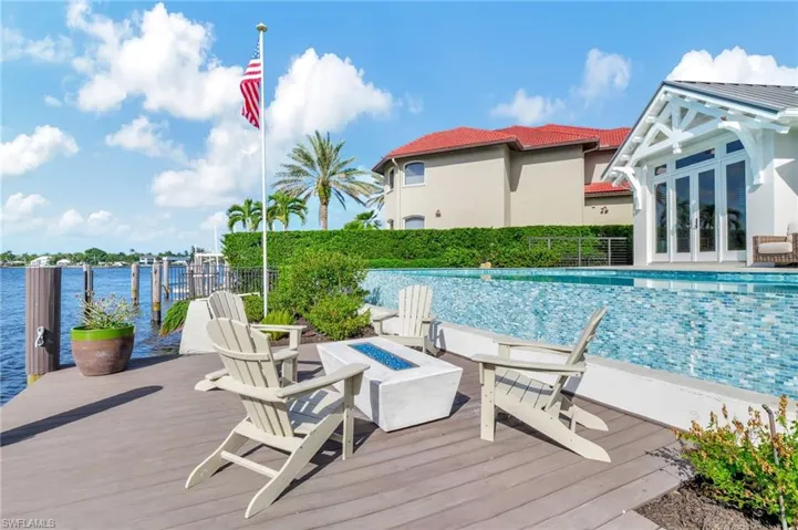 View of pool featuring an outdoor fire pit, french doors, and a deck with water view