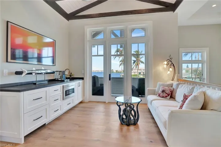 Living room featuring vaulted ceiling, a water view, and light hardwood / wood-style floors