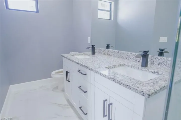 Full bathroom with double vanity and light marble finish flooring