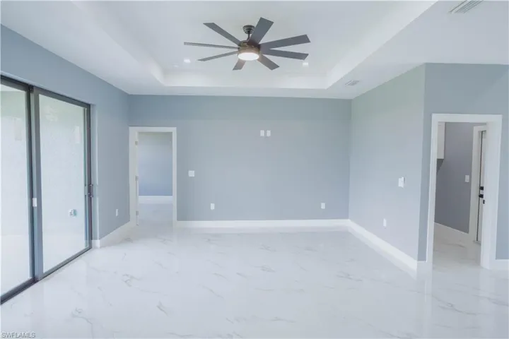Unfurnished bedroom with a raised ceiling, access to exterior, light marble finish floors, a ceiling fan, and recessed lighting