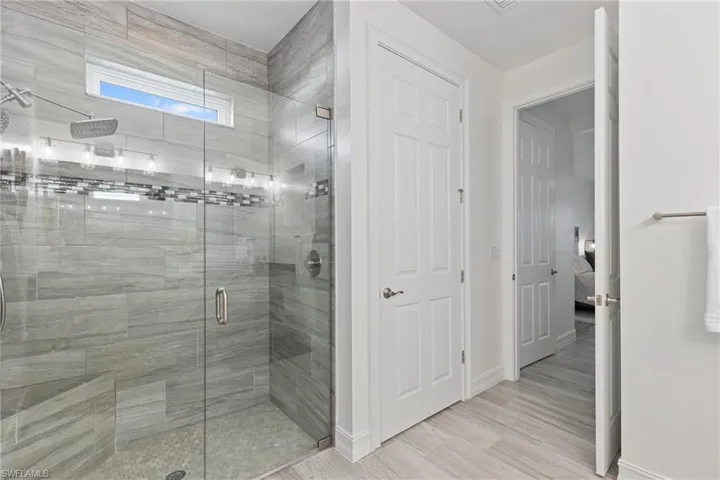Bathroom with hardwood / wood-style flooring and a shower with shower door