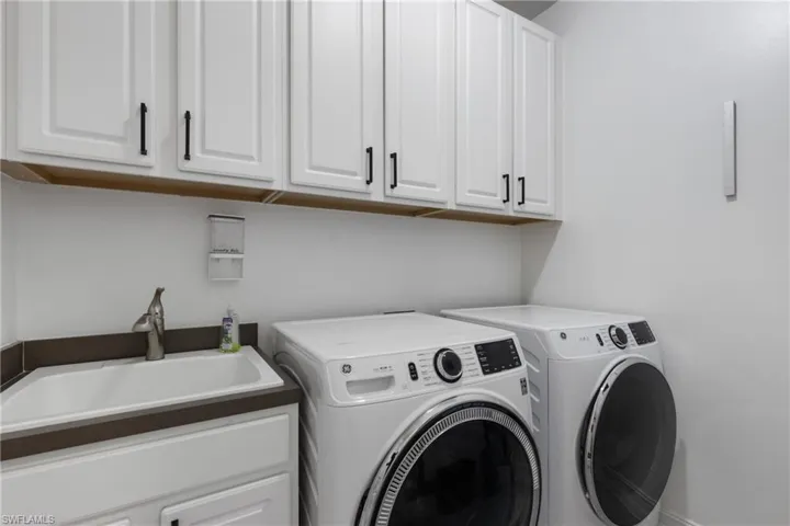 Washroom featuring cabinets, sink, and washing machine and clothes dryer