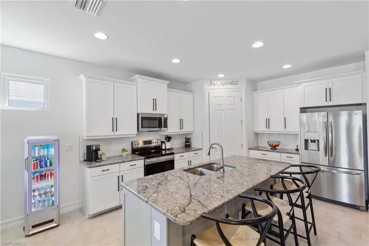 Kitchen featuring white cabinetry, appliances with stainless steel finishes, sink, and a kitchen island with sink