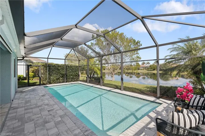 View of pool with a patio, glass enclosure, and a water view