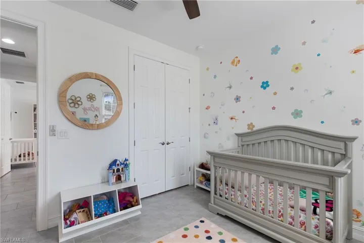 Bedroom featuring a nursery area, ceiling fan, and a closet