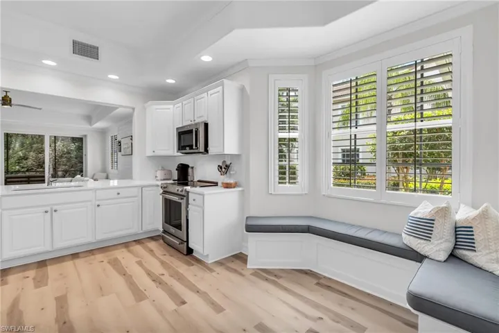 Kitchen featuring stainless steel appliances, white cabinetry, light wood-style floors, recessed lighting, and ornamental molding