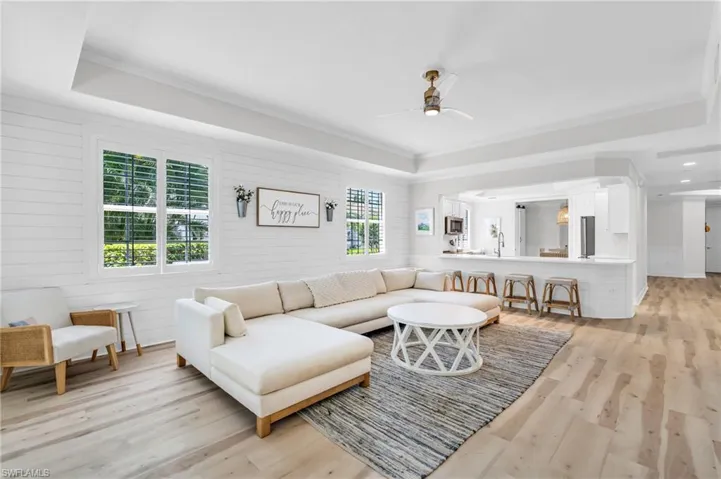 Living area featuring ceiling fan, light wood finished floors, crown molding, and a tray ceiling